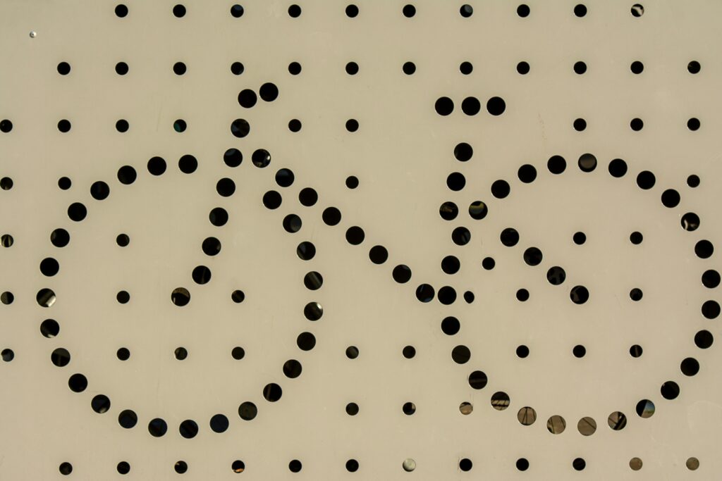 Artistic bicycle symbol formed with circular perforations on a surface.